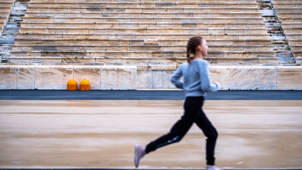 A girl runs in a historic stadium with empty stands, symbolizing youthful energy and ancient architecture.
